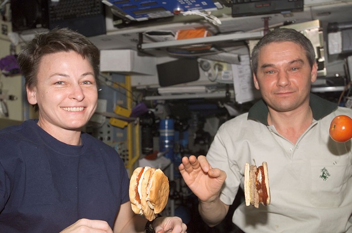 אסטרונאוטים אוכלים המבורגרים בתחנת החלל הבינאלומית. הרטבים משמשים כדבק, שמונע מההמבורגר להתפרק. | צילום: נאס