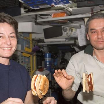 אסטרונאוטים אוכלים המבורגרים בתחנת החלל הבינאלומית. הרטבים משמשים כדבק, שמונע מההמבורגר להתפרק. | צילום: נאס